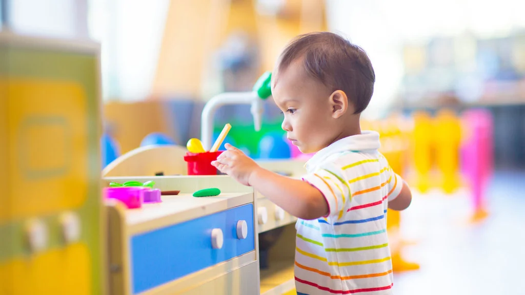 Toddler practicing independent play and problem-solving with a toy kitchen at Great Beginnings Preschool.