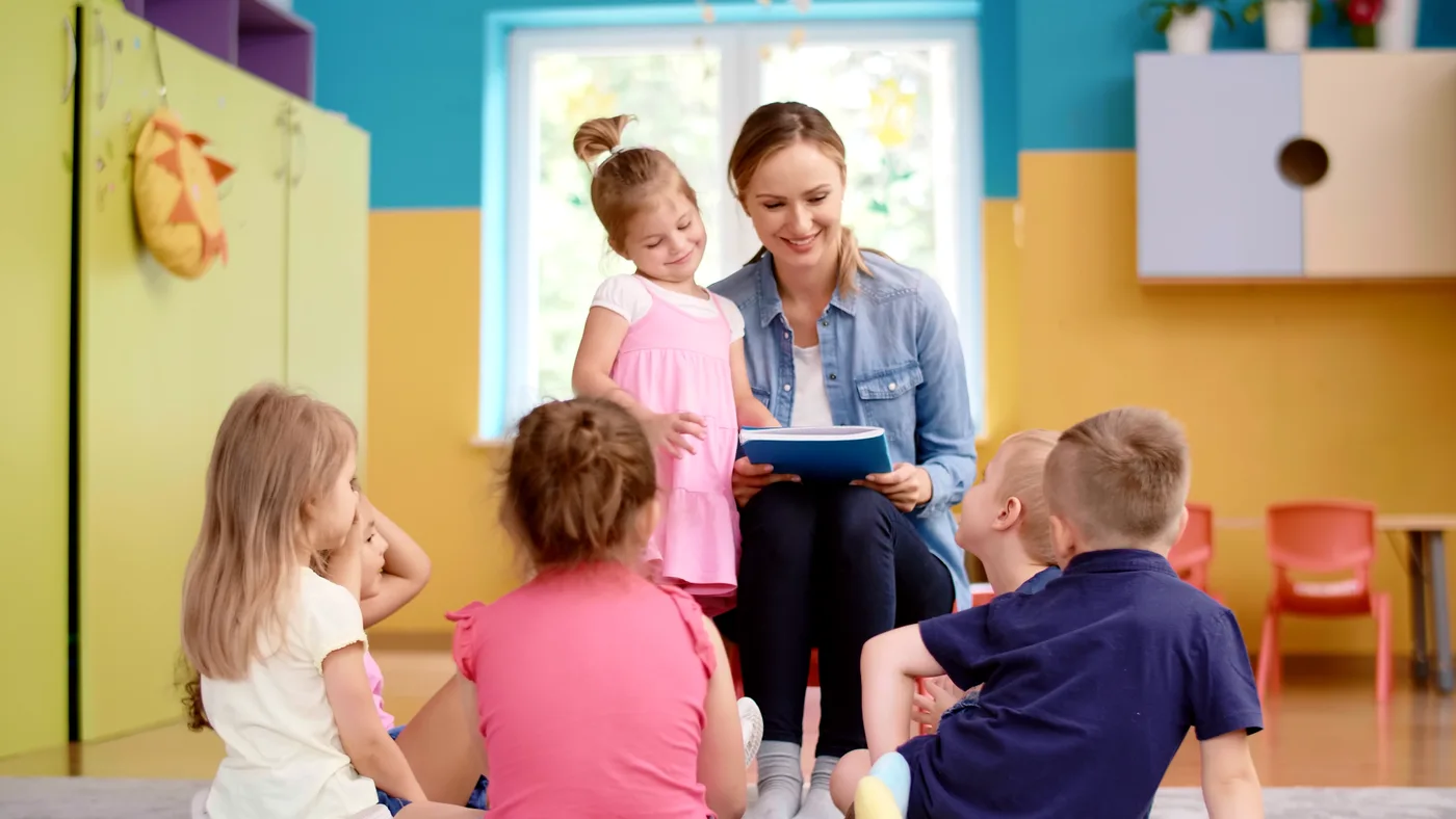A teacher sharing a picture book with a group of young children