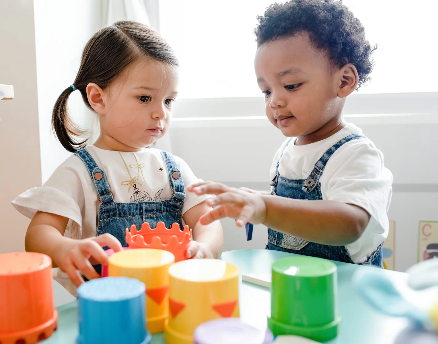 Two young children exploring colorful stacking toys together